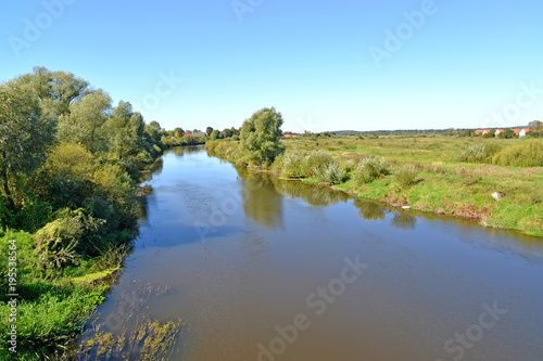 View on the Pregolya River with houses on the horizon in summer day. Znamensk  Kaliningrad region