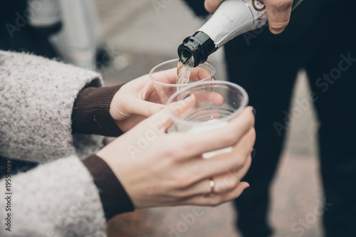 pouring champagne to glasses in female hands