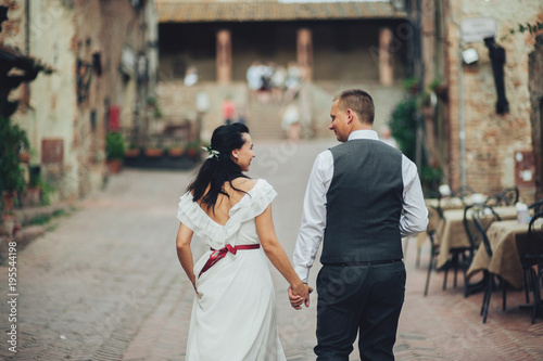 Happy bride and groom walking in an old Italian village