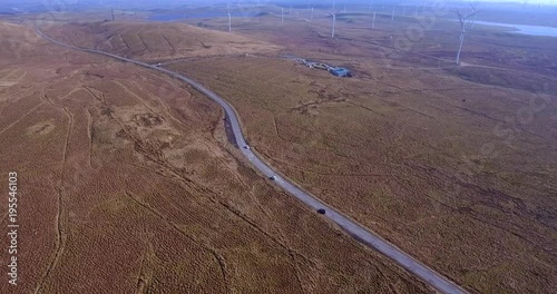 Aerial footage of Whitelees windfarm and visitor centre near Eaglesham in Scotland. Vast array of  turning wind turbines on a bleak moor. photo