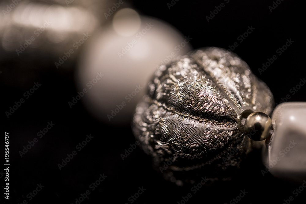 A part of a white bead necklace with gold and silver elements A part of a white bead necklace with gold and silver elements
