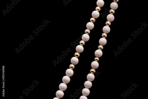 A part of a white bead necklace with gold and silver elements