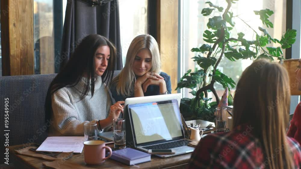 four beautiful businesswomen working in a cafe with a laptop four beautiful businesswomen working in a cafe with a laptop