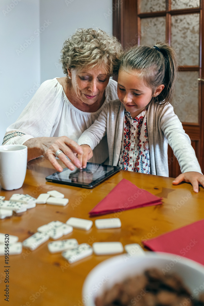 Grandmother and granddaughter playing with the tablet in the living room Grandmother and granddaughter playing with the tablet in the living room