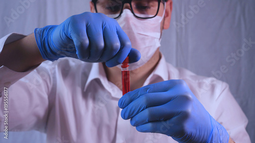 фотографія Lab work, Doctor holds a test tube, in a medical mask and glasses, takes the test from a test tube in blue rubber gloves, analysis, blood, DNA, test tube stand