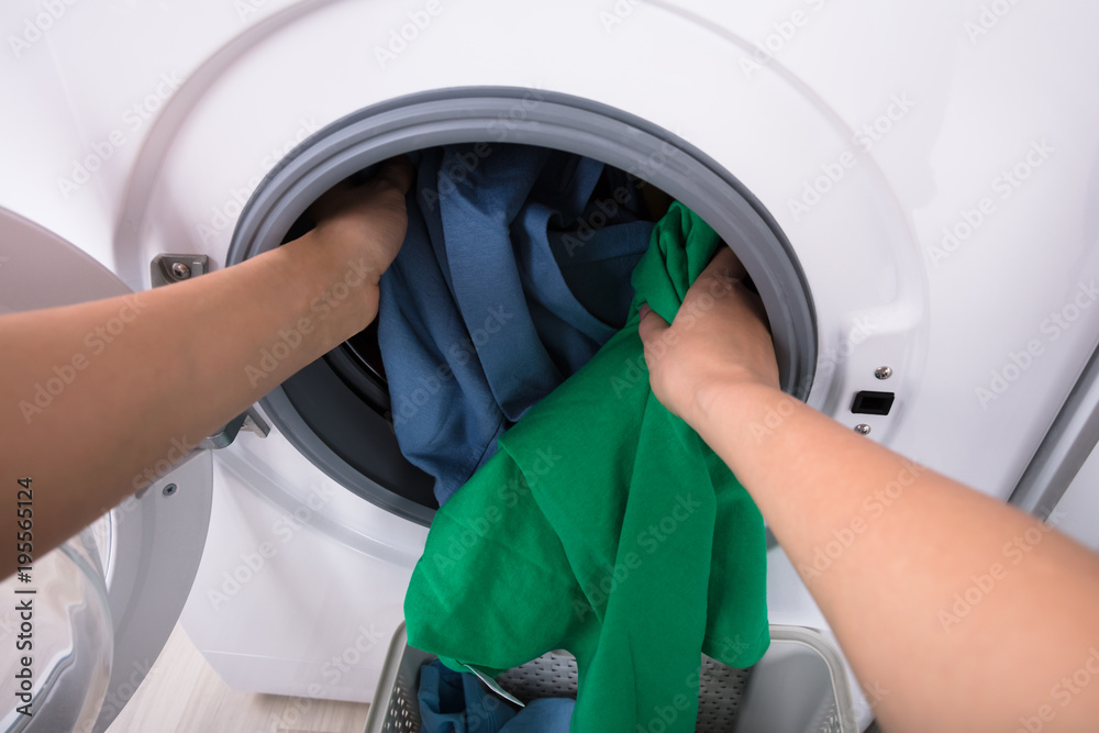 Woman Putting Clothes In Washing Machine Woman Putting Clothes In Washing Machine