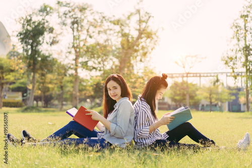 Young women students together study reading book in university and knowledge at outside or park campus relaxing smile in summer season