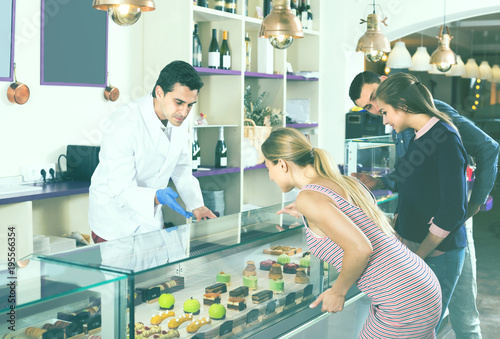 Friends are choosing cakes from showcase photo