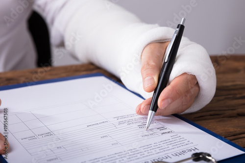 Man With Broken Arm Filling Health Insurance Claim Form