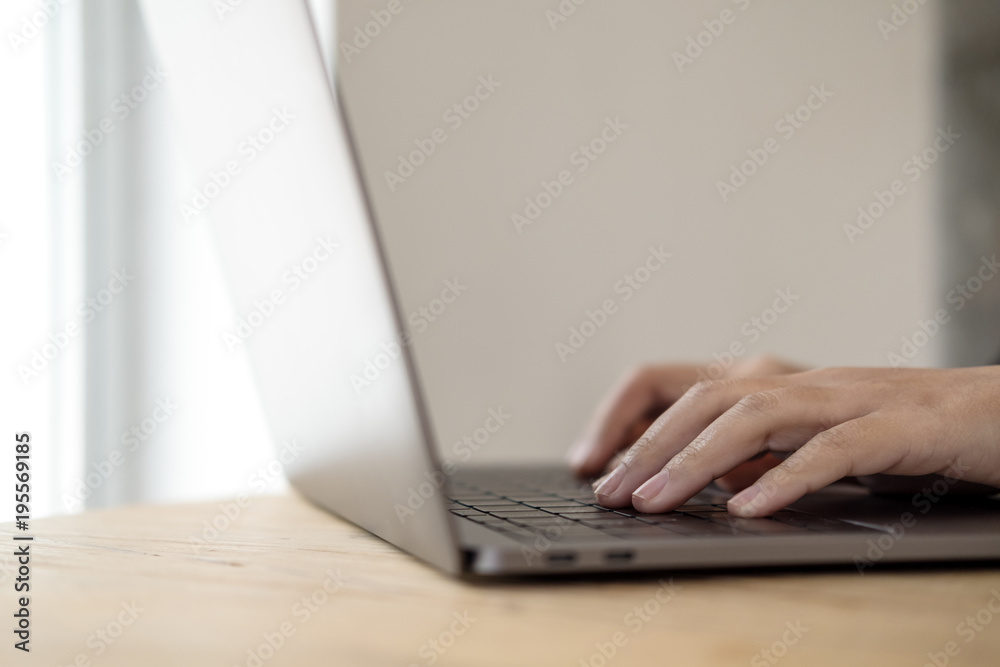 Closeup image of hands working and typing on laptop keyboard on wooden table Closeup image of hands working and typing on laptop keyboard on wooden table