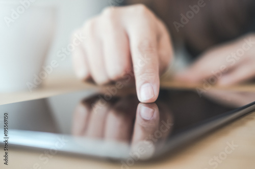 Closeup image of a woman's hand pointing , touching and using tablet pc