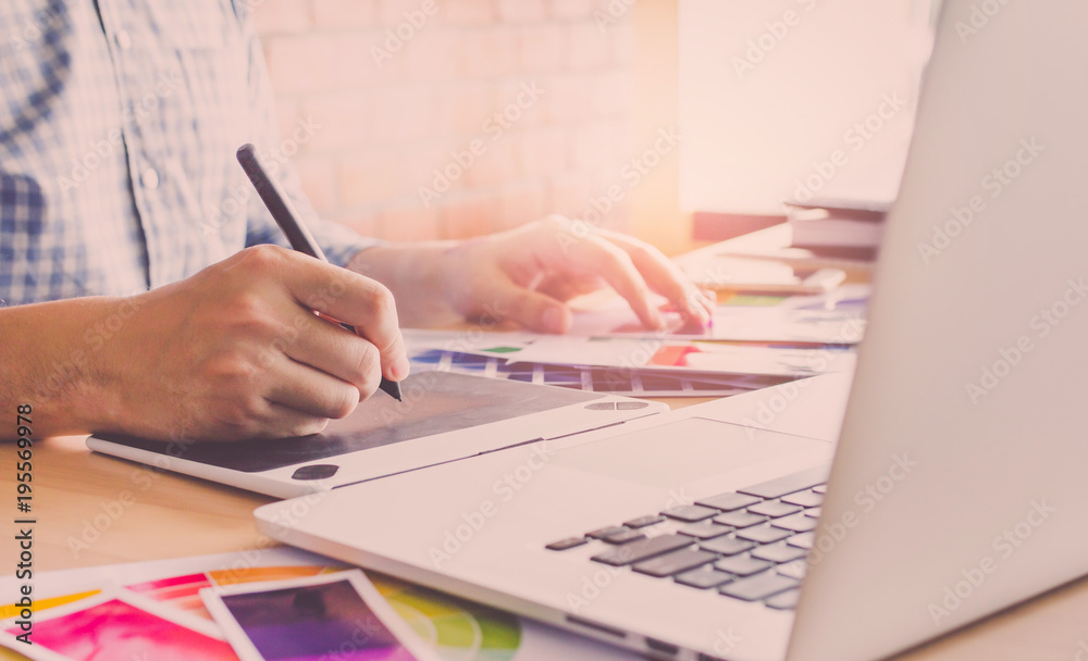 Fototapeta premium Designer graphic creative ,Man holding pen pointing Working on laptop in office with sunset background,Selective focus.