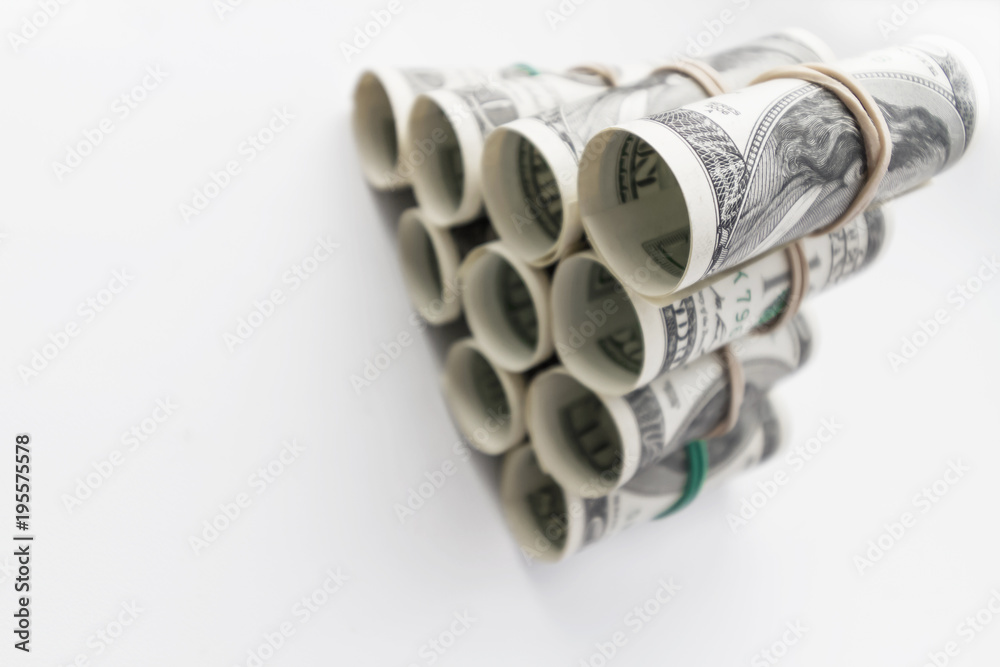 American one hundred dollar bills rolled and stacked in a pyramid. Light background, closeup, selective focus American one hundred dollar bills rolled and stacked in a pyramid. Light background, closeup, selective focus
