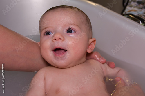 Cute infant baby boy taking bath smile