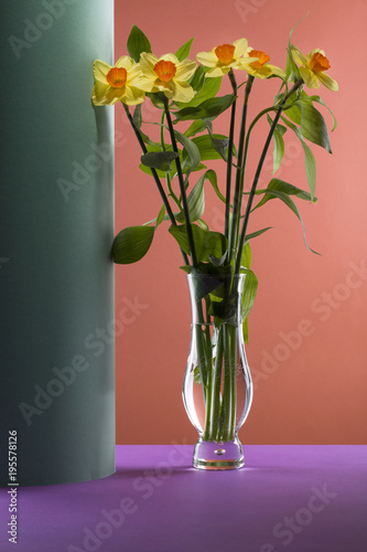 Fototapeta Naklejka Na Ścianę i Meble -  Bouquet of daffodils in a glass vase on a colored background