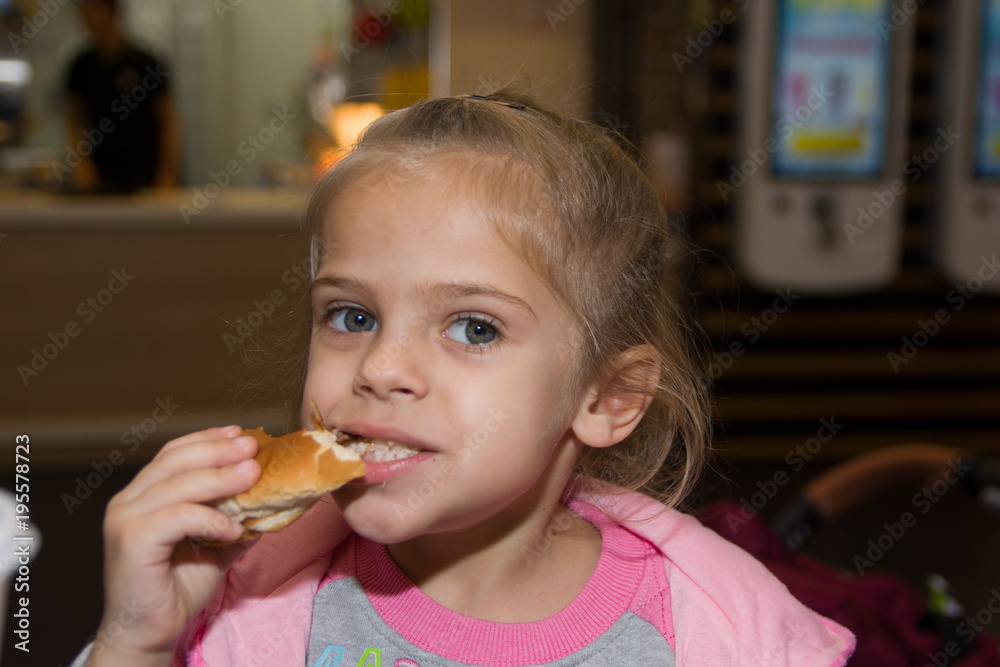 Cute little blond girl eating a hamburger Cute little blond girl eating a hamburger