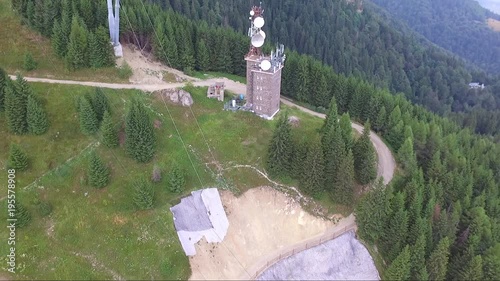 Communications tower and cable cars beside lush mountain pine forest. Aerial view photo