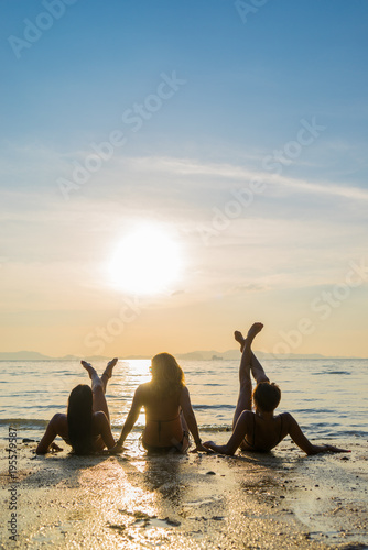 Silhouette of three girls on the beach at sunset