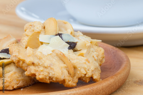 close-up butter cashew cookies on wooden dish with blurred white coffee cup on the background