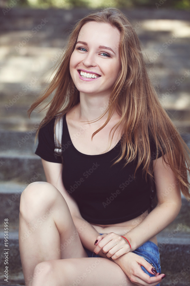 Fototapeta premium young girl in shorts, sits on the steps. emotional portrait.