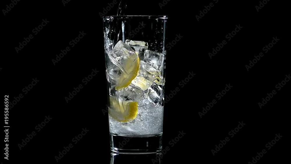 water with lemon and ice in a glass on a black isolated background
