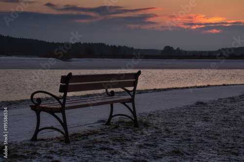  Empty wooden bench standing by the river in the morning sun light