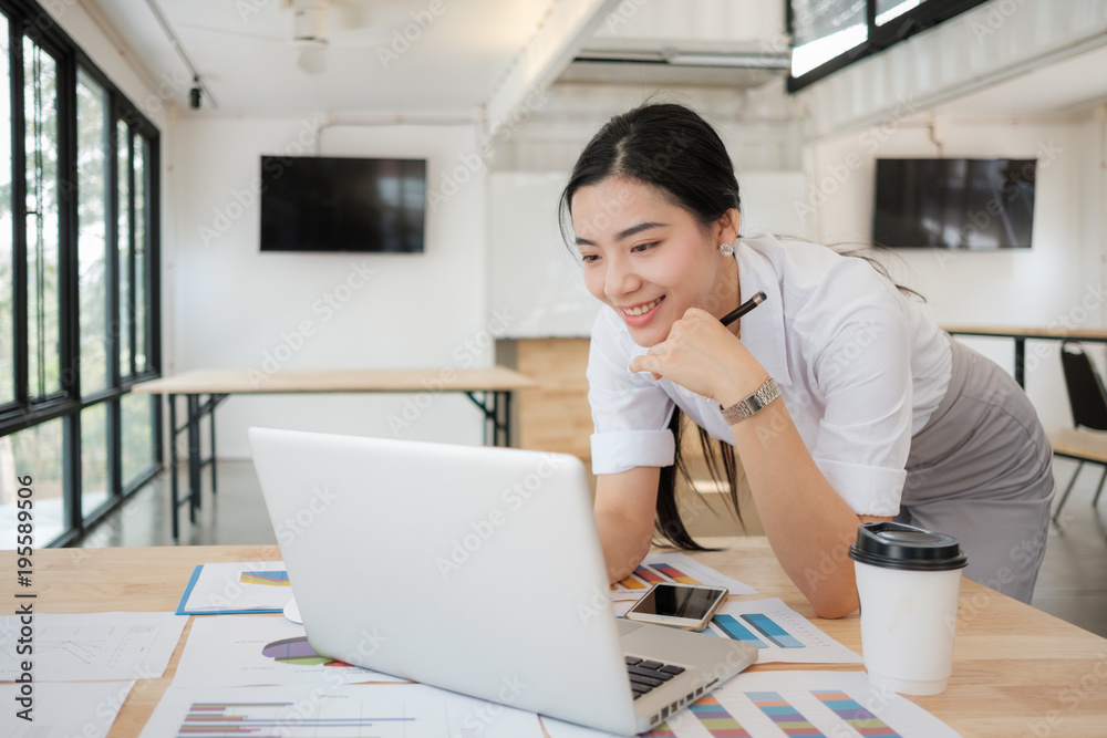 Portrait of smiling pretty young business woman on workplace, Calculating the cost of postage of a small package, Small business enterprise concerns for online Shopping Portrait of smiling pretty young business woman on workplace, Calculating the cost of postage of a small package, Small business enterprise concerns for online Shopping