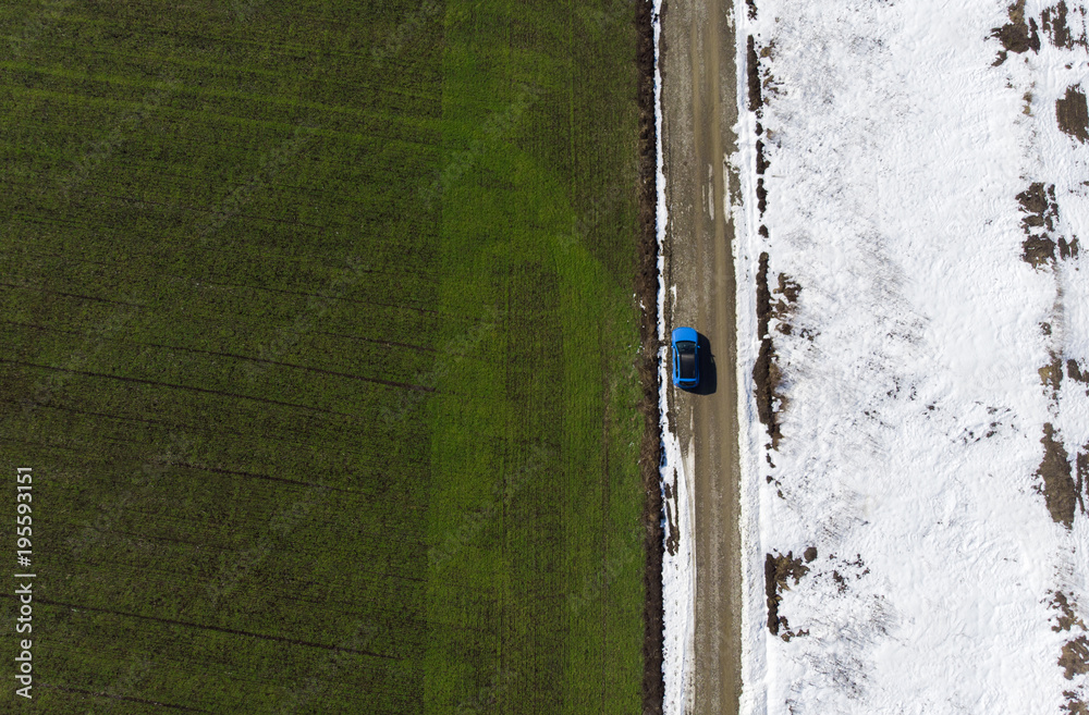 aerial view of green spring field and snow from the drone. car in the road scene aerial view of green spring field and snow from the drone. car in the road scene