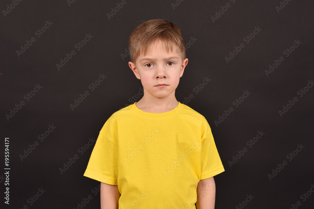 Emotional guy. Portrait of a boy in a T-shirt. Shooting in the studio. A young man on a black background. Emotional guy. Portrait of a boy in a T-shirt. Shooting in the studio. A young man on a black background.