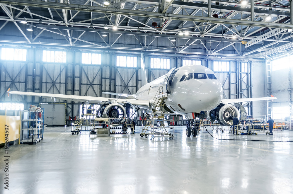 Naklejka premium Samolot pasażerski na utrzymanie naprawy silnika i kadłuba w hangarze lotniskowym.