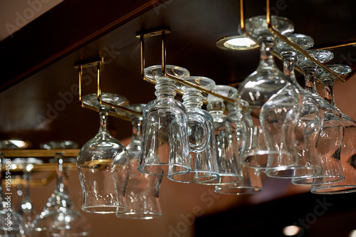 Wine glass glasses hang on the holders above the bar. The atmosphere of the evening pub, restaurant, cafe