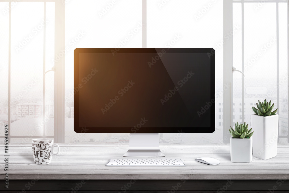 Computer display with blank screen for mockup in office or work room. Window and sun light in background. Cup of coffee and two plants beside. Computer display with blank screen for mockup in office or work room. Window and sun light in background. Cup of coffee and two plants beside.