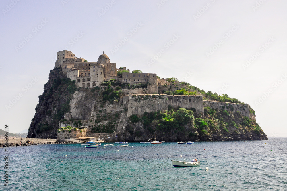 The island of Ischia, Campania / Italy, March 8, 2018. Italian summer holidays on Ischia island, blue sea and sky on a Sunny day, beach and castle on a rock, in the sea there are many white yachts