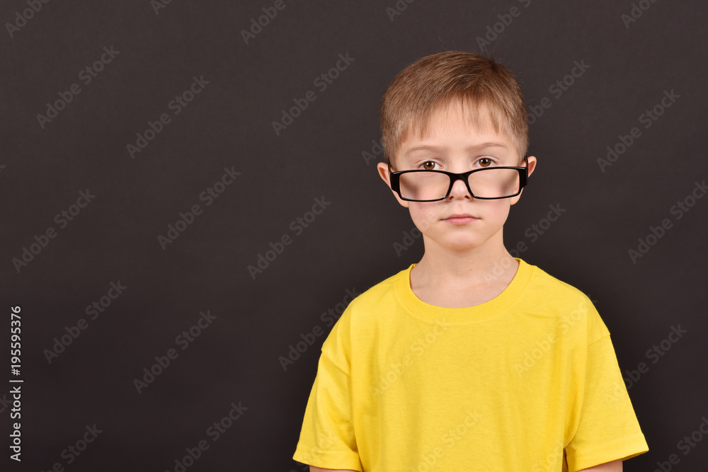 A boy in glasses. A child's portrait on a black background.
