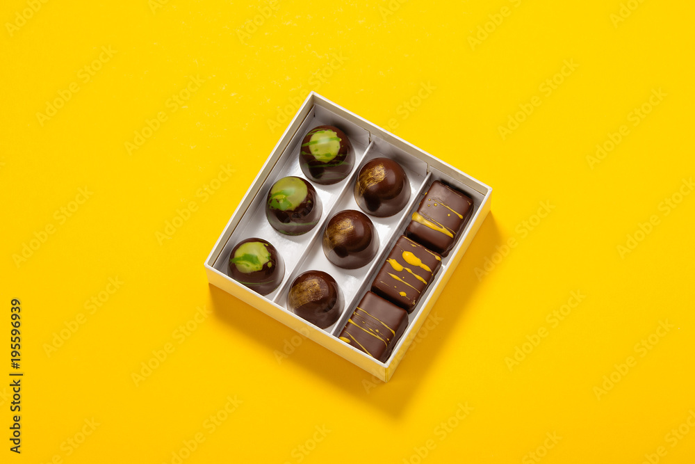 Assortment of luxury bonbons in box on bright yellow background