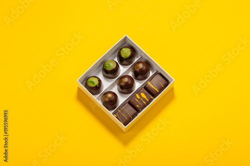 Assortment of luxury bonbons in box on bright yellow background