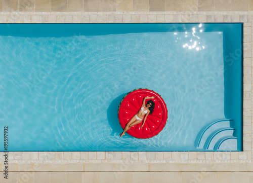 Young woman floating on inflatable mattress in pool