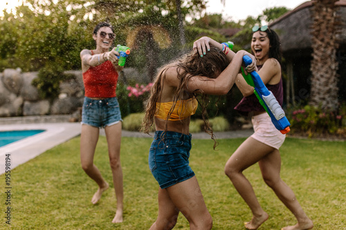 Crazy female friends having water gun battle