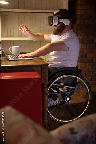 Disabled man in virtual reality headset using laptop photo