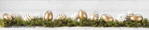 Photography easter decoration, gold painted eggs on moss against a gray white wooden backgro