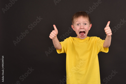 Emotional guy. Portrait of a boy in a T-shirt. Shooting in the studio. A young man on a black background.