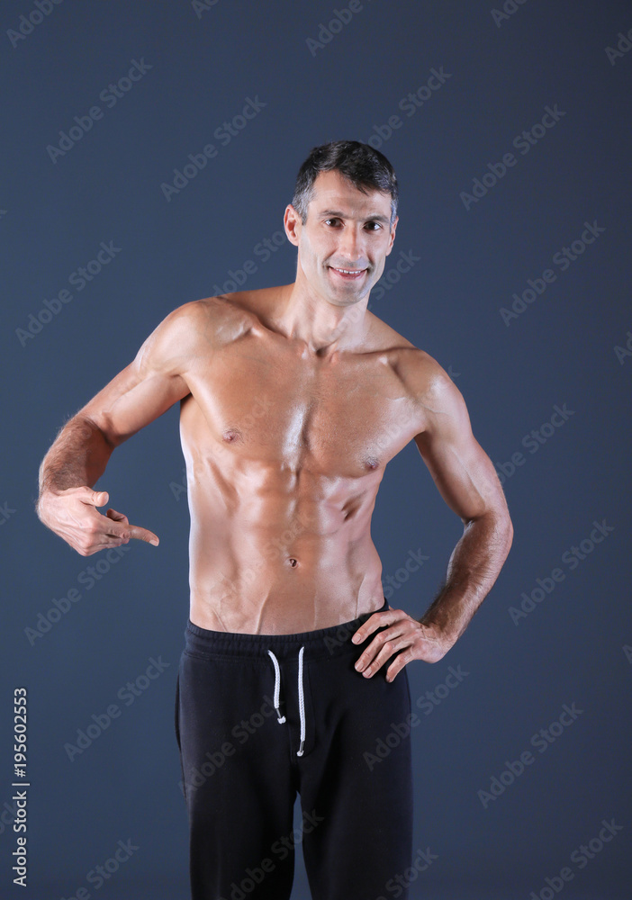 Fototapeta premium muscular man. Muscular man on a grey background showing muscles. Fitness instructor. Fitness professional. Workout. Men's fitness.