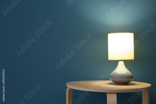 Elegant lamp on table near color wall photo