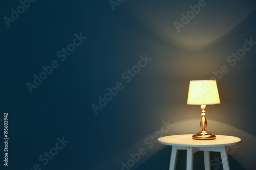 Elegant lamp on table near color wall