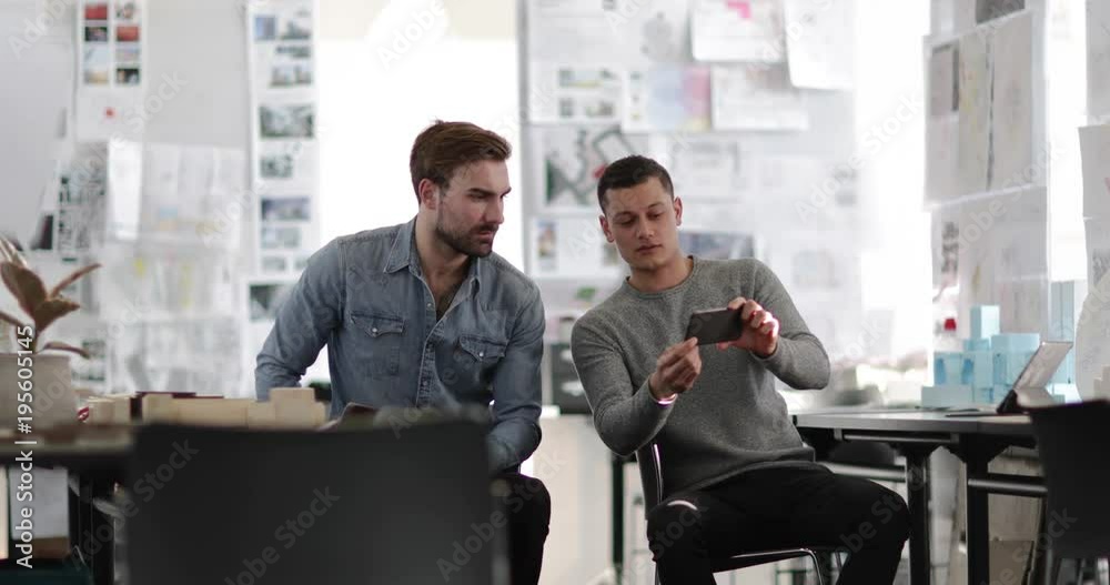 Designers looking at smartphone in creative workspace