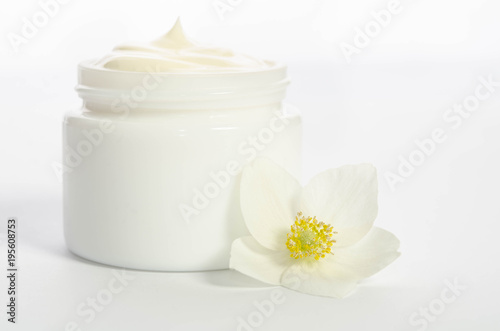 Cute flower and a jar of natural body cream isolated on white background