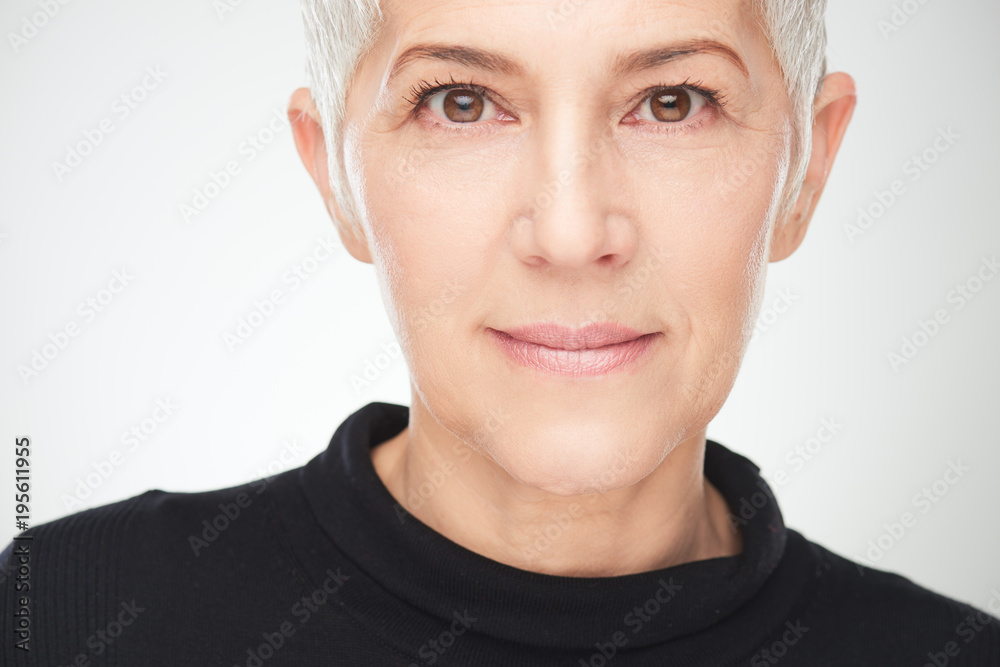 Fototapeta premium Portret piękna starsza kobieta przed białym tłem.