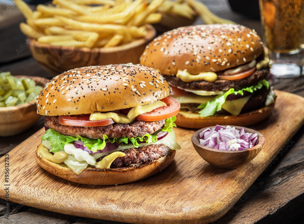 Hamburgers and French fries on the wooden tray. Hamburgers and French fries on the wooden tray.