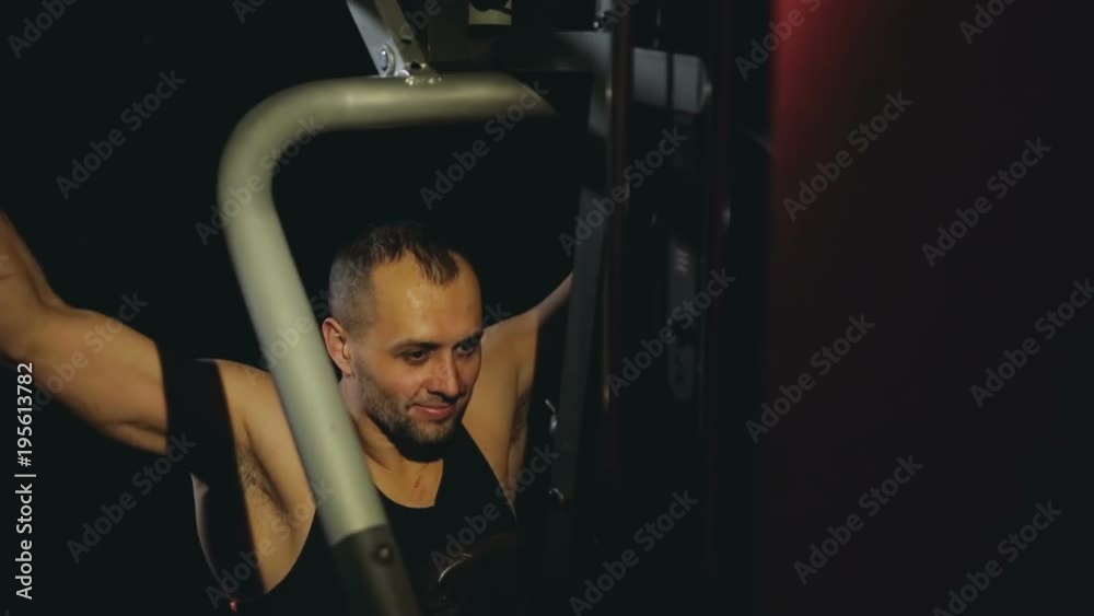 guy trains shoulders at the trainer in the dark gym guy trains shoulders at the trainer in the dark gym