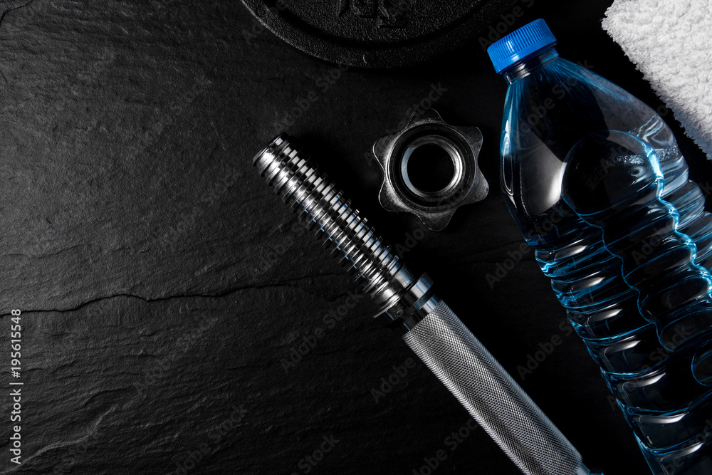 Dumbbell, bottle of water and white towel on black background. Gym accesories. Dumbbell, bottle of water and white towel on black background. Gym accesories.